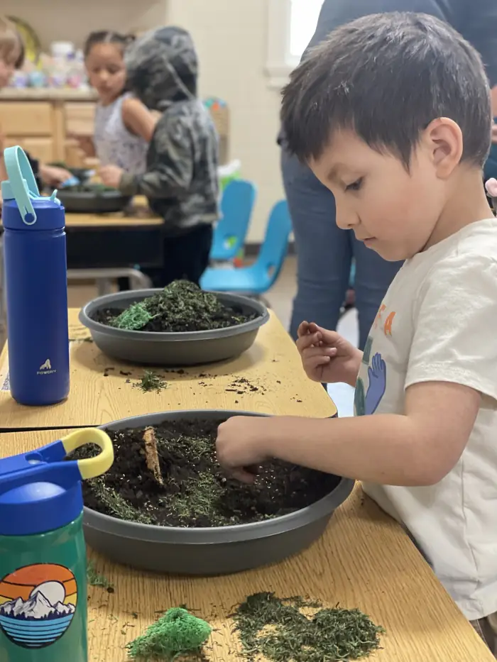 A young Cornerstone student building an Easter tomb garden with soil and moss
