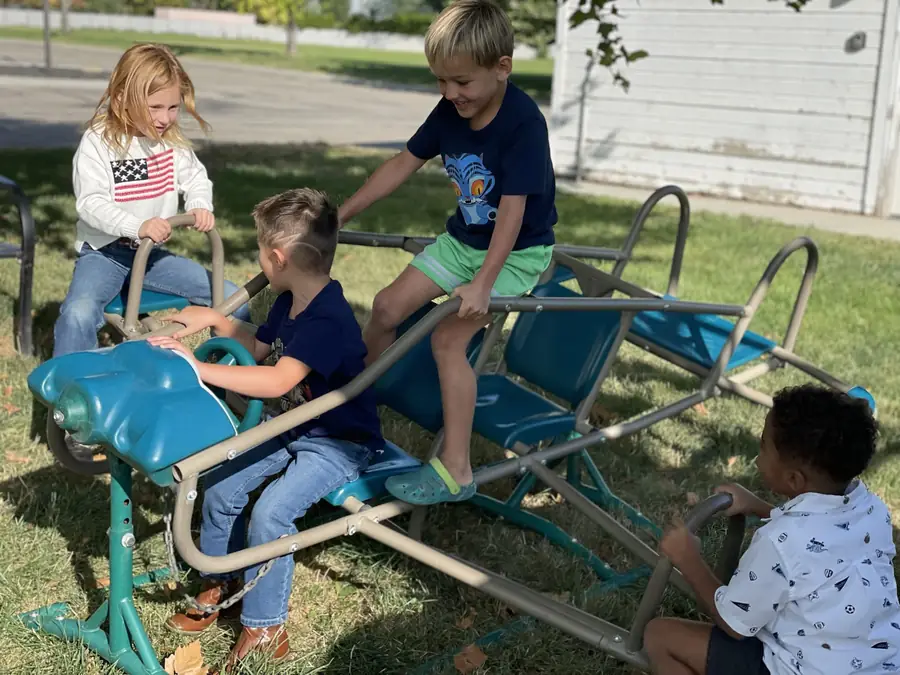 Cornerstone students of different ages playing together on the playground seesaw